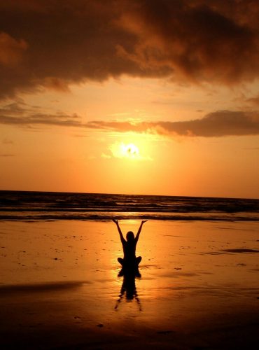 Peaceful meditation silhouette at sunset on a serene beach.